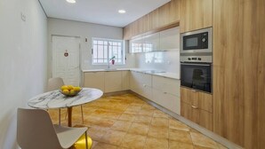 Una cocina moderna con armarios de madera, encimera de mármol y horno integrado.