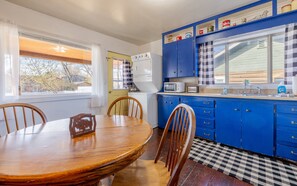 A kitchen with blue cabinets, a microwave, a sink, and a dining table with chairs.