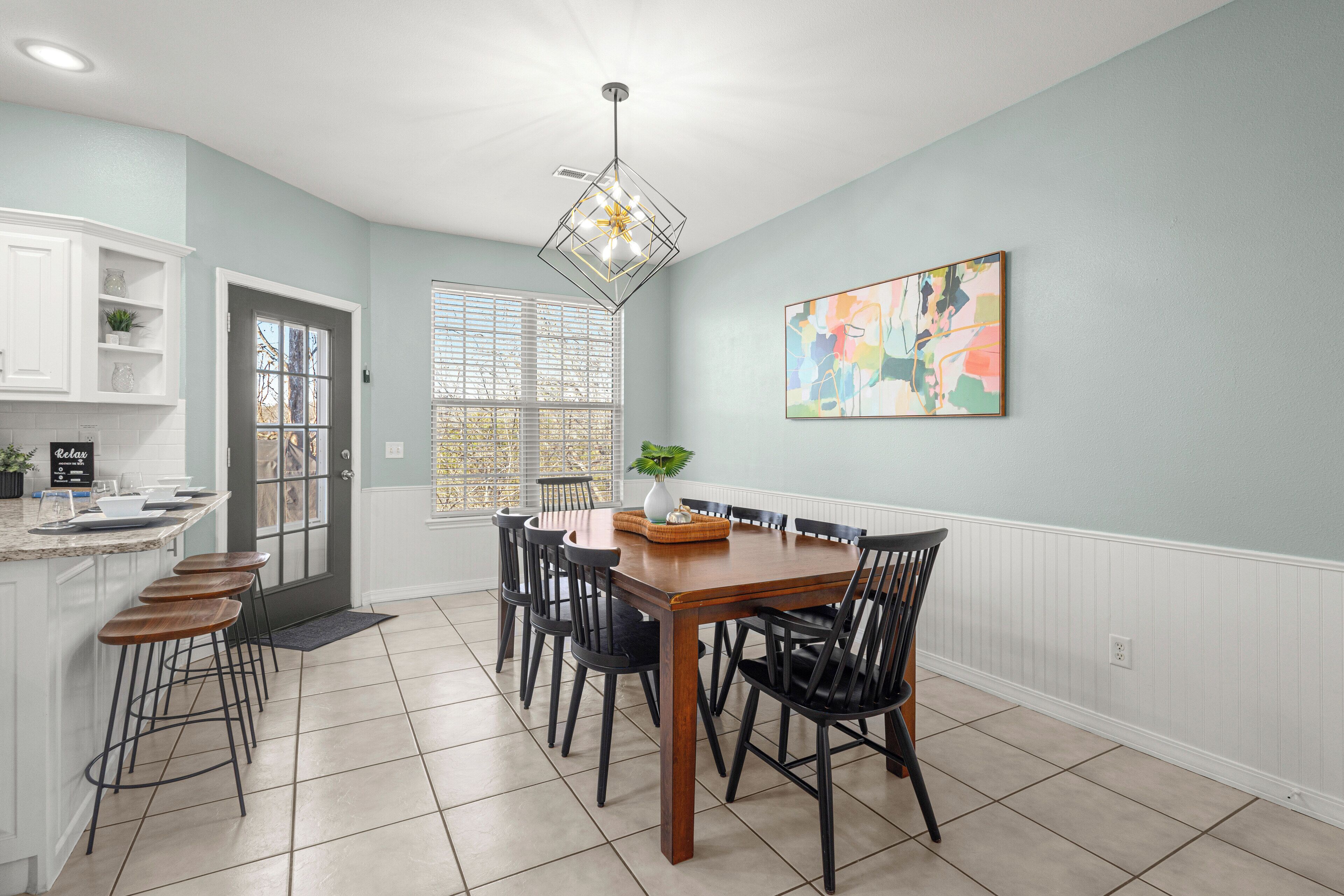 A dining area with a wooden table, black chairs, and a pendant light.