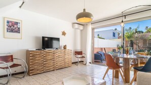 Een moderne woonkamer met een flatscreen televisie, houten meubels en een eethoek met stoelen en een tafel.