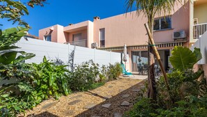Een woongebouw met een patio, voorzien van een pad van natuursteen, buitenmeubilair en weelderige beplanting.