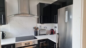 Eine moderne Küche mit Schwarz-Weiß-Design, ausgestattet mit einem Edelstahl-Kühlschrank, einer Kaffeemaschine und einem Toaster.