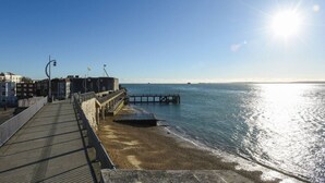 Ein Steg, der sich ins Meer erstreckt, mit blauem Himmel darüber.