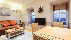 Ein Wohnzimmer mit einer Couch, einem Couchtisch, einem Fernseher und Korbstühlen.