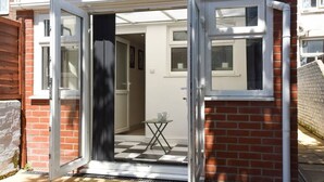 Une entrée d’immeuble d’habitation avec une porte vitrée, une petite table et un sol à carreaux.