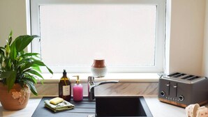 A kitchen with a sink, a toaster, a potted plant, and a window with blinds. - Emsworth`s Cosy Bungalow | Sleeps 3! (West Sussex)
