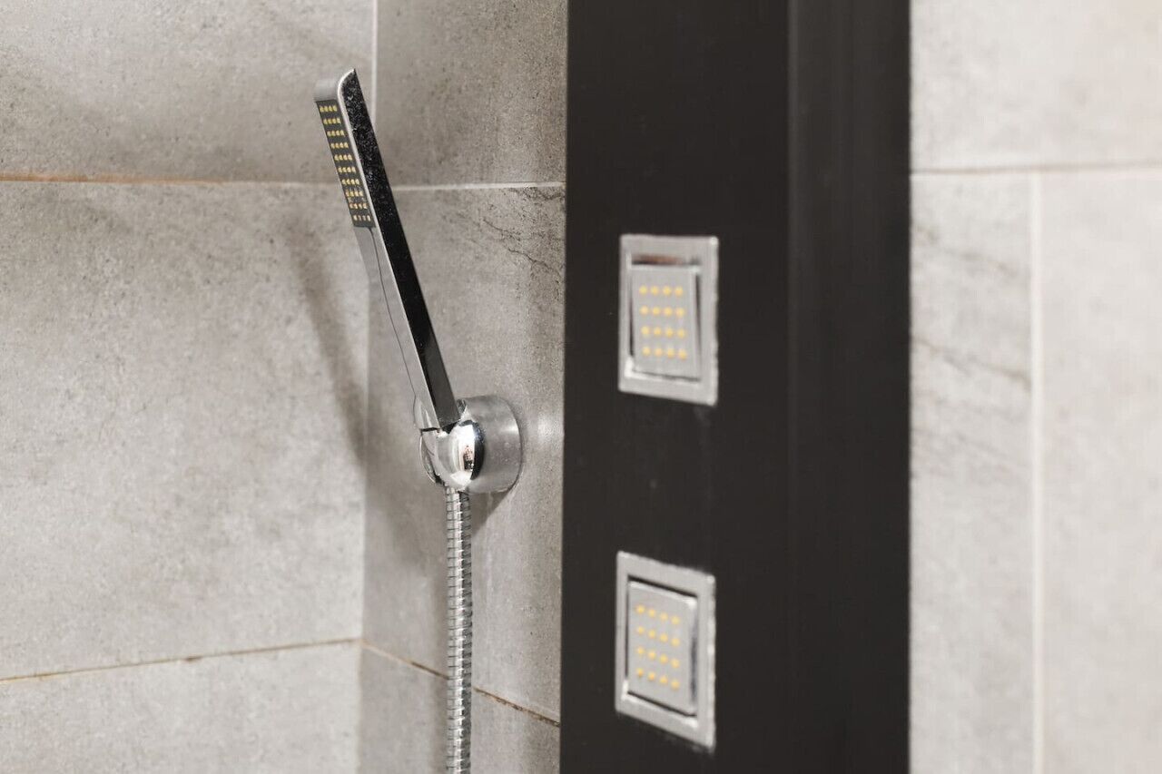 Une douche équipée d’un pommeau de douche à main et d’un panneau de commande.