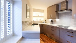 Una cocina moderna con horno empotrado, pileta y extractor de acero inoxidable.