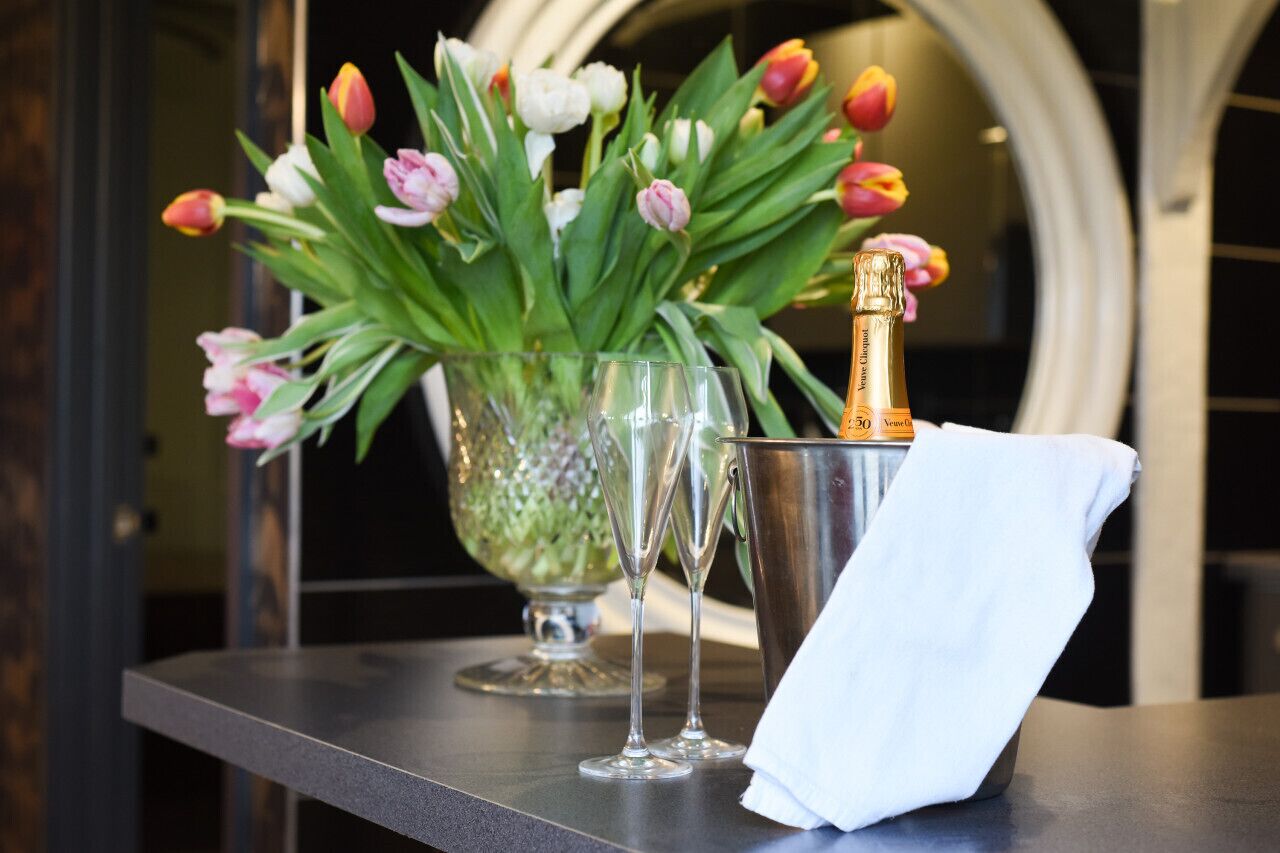 Une table avec un vase de tulipes, deux coupes à champagne et une bouteille de champagne.