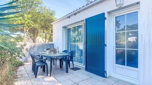 Un patio con una mesa y sillas, una puerta azul y vistas del entorno.