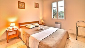 Un dormitorio con cama, mesitas de noche, ventana y radiador.
