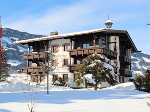 A traditional chalet-style building with a balcony, surrounded by snow-covered trees and mountains in the background. - Römerhof by Interhome (Fügen)