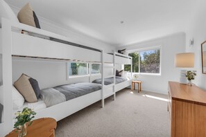 A modern, well-lit room with bunk beds, a small table, and a desk. - A Short Time - 2 Bedroom House (Merimbula)