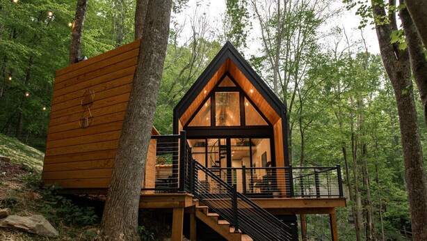 A cabin with a wooden exterior, a balcony, and a staircase leading to the entrance.