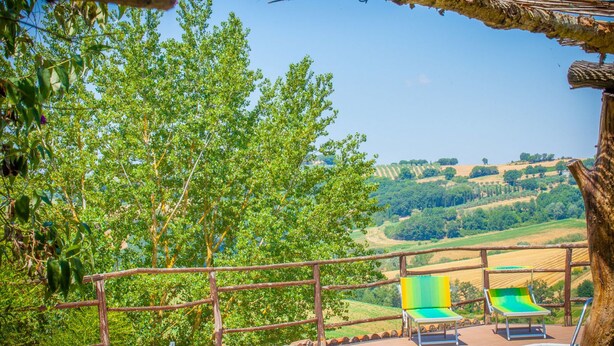 A poolside area with wooden railings, two lounge chairs, and a view of rolling hills. - Tra Cielo e Terra by Interhome (Todi)