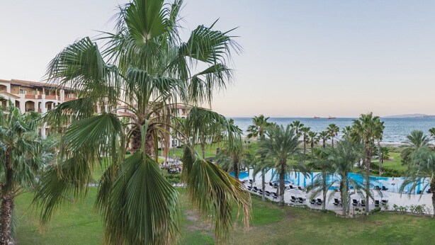 Et resort med poolområde, palmer og havudsigt.