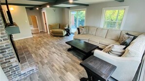 A spacious living room with a fireplace, a sofa, a coffee table, and a dining table.