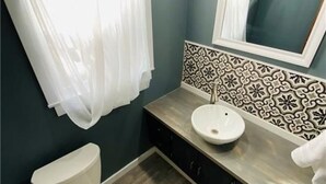 A bathroom with a toilet, sink, and a mirror.