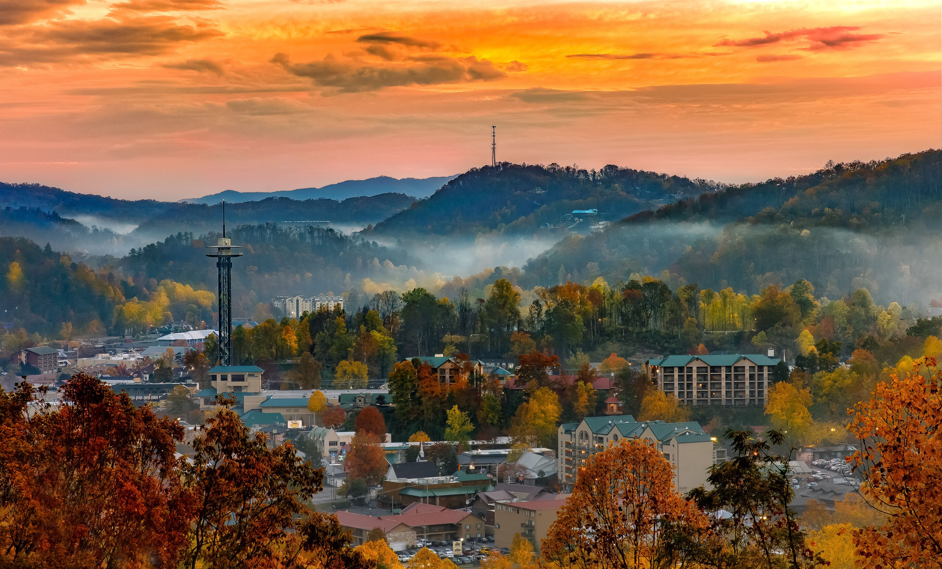 A town with autumn foliage, a prominent tower, and a mix of residential and commercial buildings.