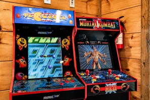 Deux bornes d’arcade, l’une pour Pac-Man et l’autre pour Mortal Kombat, dotées de commandes par joystick et de graphismes colorés.