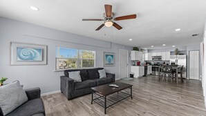 A spacious living room with a gray sofa, a coffee table, and a ceiling fan. - 🐾  Dog Friendly, Spacious Beach Retreat, only Steps to Sugary Sand, Conveniences and all the Fun! (Fort Myers Beach)
