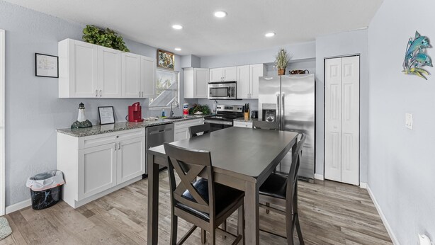 A modern kitchen with white cabinets, a central island, stainless steel appliances, and a small plant on the counter. - 🐾  Dog Friendly, Spacious Beach Retreat, only Steps to Sugary Sand, Conveniences and all the Fun! (Fort Myers Beach)