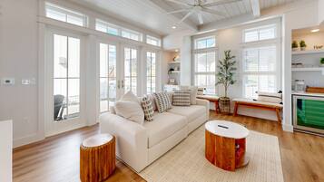 A spacious living room with a white sofa, wooden side tables, and a ceiling fan.