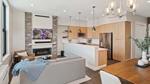 A modern living room with a fireplace, a sofa, and a dining area with a wooden table.