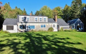 A two-story house with a garage, a covered porch, and a small detached building.
