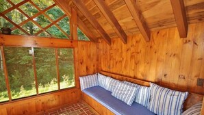 A wooden cabin interior with a built-in bench and large windows.