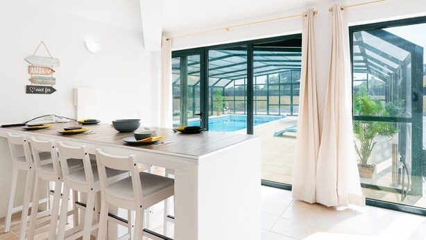 Una cocina moderna con comedor, ventanas amplias y vista a una piscina.