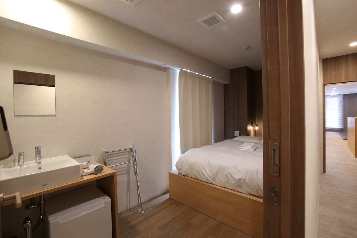 Een moderne hotelkamer met een houten bed, een ingebouwd wastafelmeubel en een spiegel.
