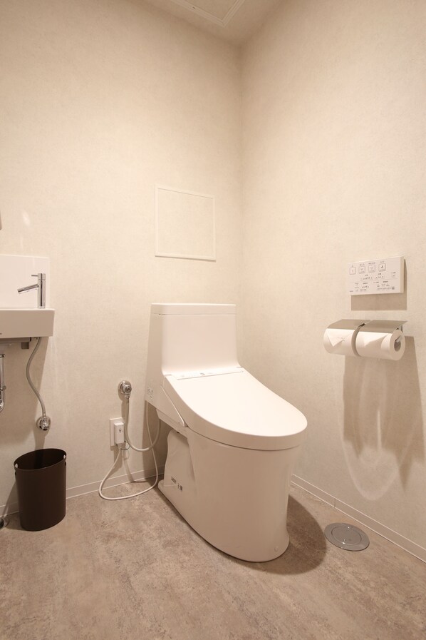 A small, modern bathroom with a toilet, sink, and a paper towel dispenser.