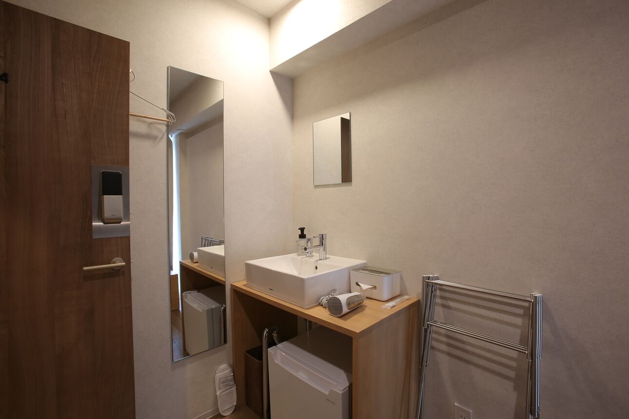 A modern bathroom with a wooden vanity, a large mirror, a sink, a towel rack, and a toilet.