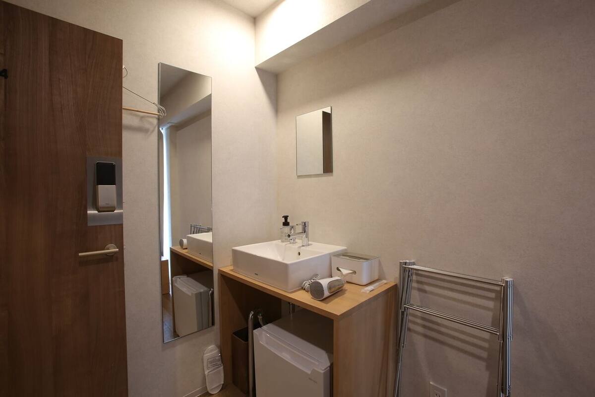 Een moderne badkamer met een houten wastafelmeubel, een grote spiegel, een wastafel, een handdoekhouder en een toilet.