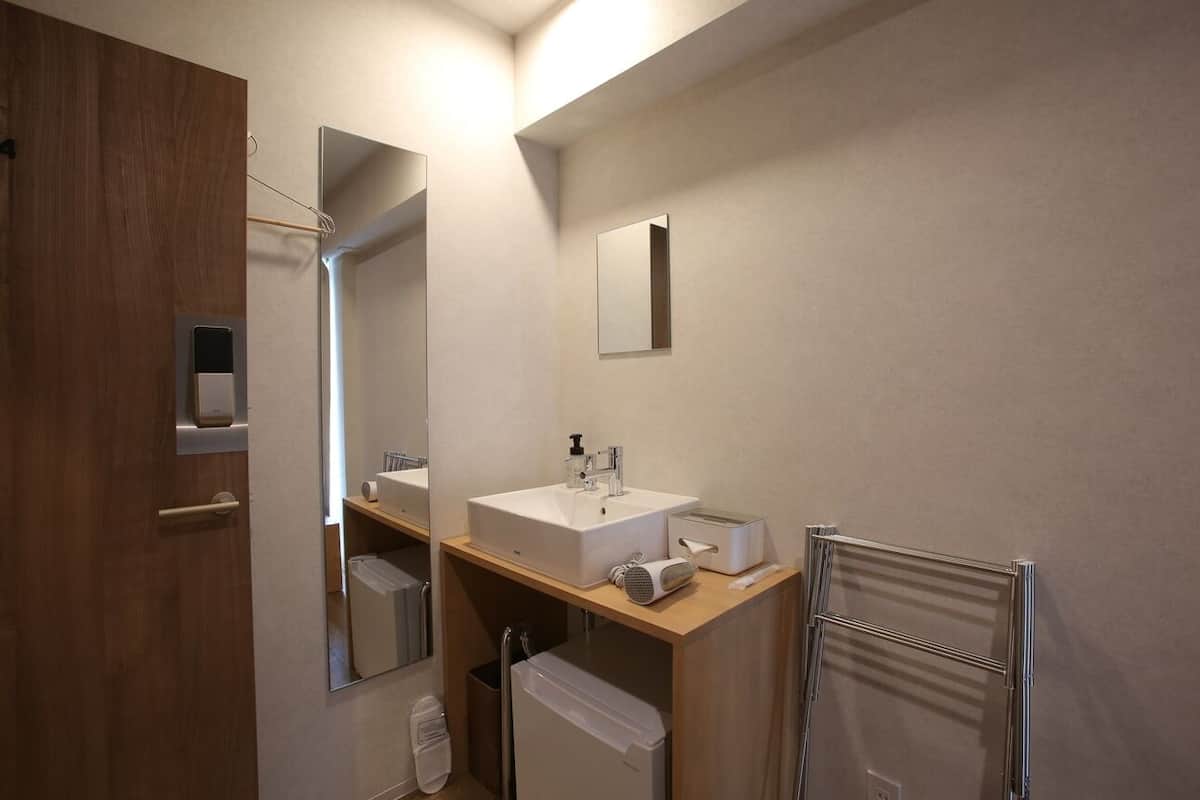 A modern bathroom with a wooden vanity, a large mirror, a sink, a towel rack, and a toilet.