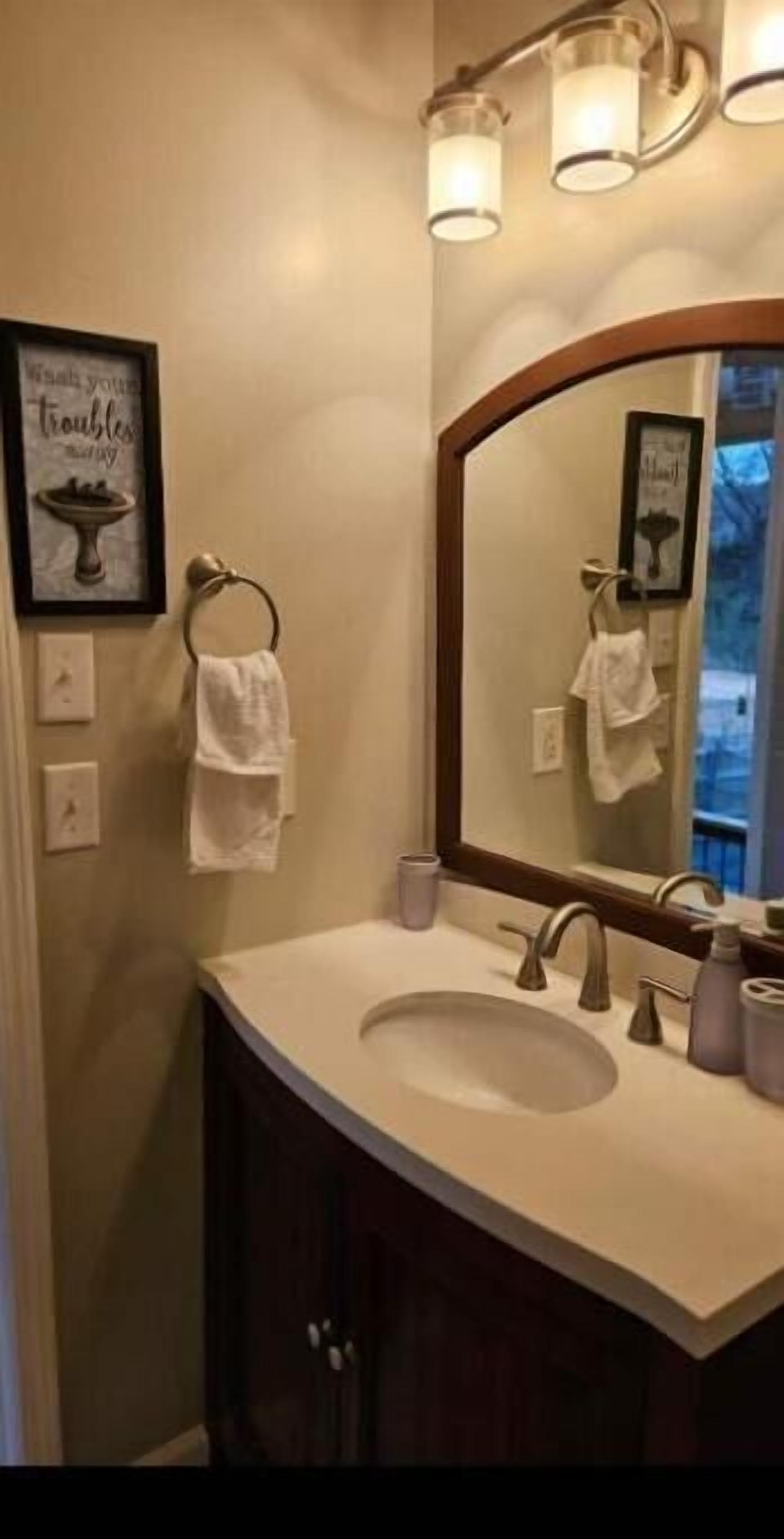 A bathroom with a large mirror, a sink with a vanity, and a towel rack.