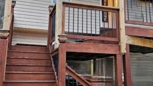 A two-story wooden house with a porch and a staircase leading to the upper floor. - Studio Kevdaya 1 (Norcross)