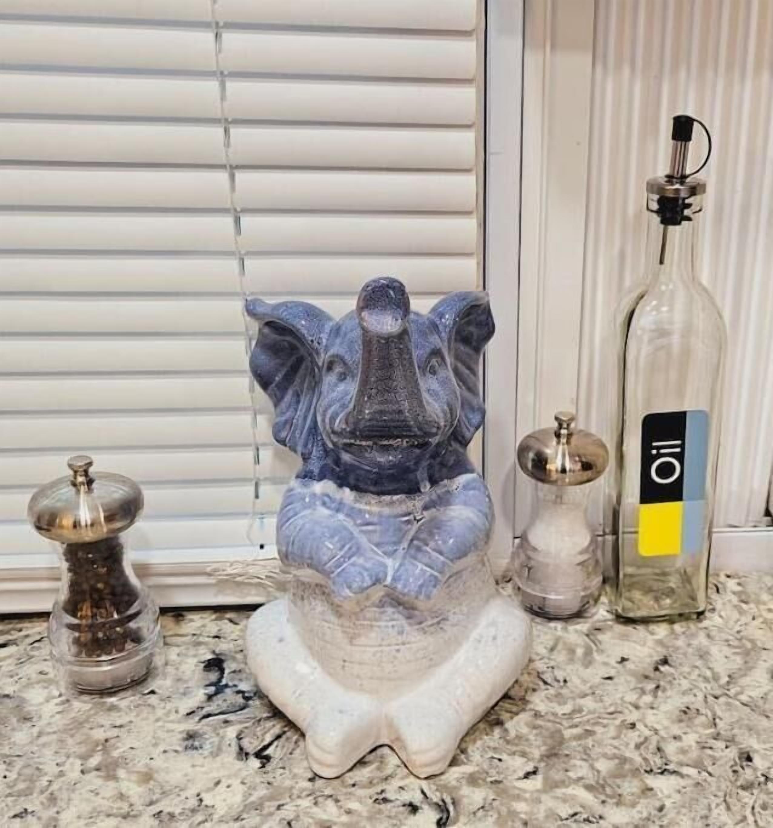 A kitchen counter with a decorative elephant sculpture, a salt shaker, a pepper shaker, and a bottle of oil.