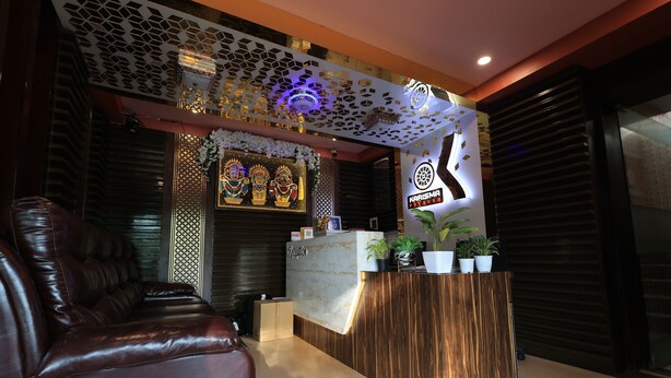 Zona de recepción con un mostrador de madera, un sofá de cuero y una pared decorativa con un logotipo.