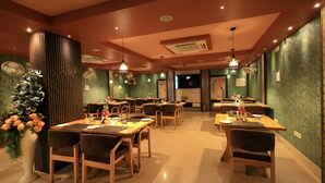 Un restaurante con varias mesas y sillas, un jarrón grande de flores y un ventilador de techo.