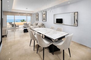 Un espace repas moderne avec une table en marbre, des chaises rembourrées et une grande fenêtre donnant sur un balcon.