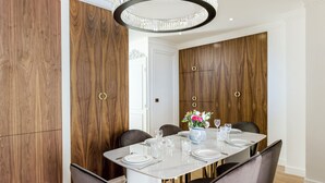 Ein Essbereich mit einem weißen Tisch, gedeckt für sechs Personen, umgeben von dunklen Stühlen, mit einer Chandelier darüber.