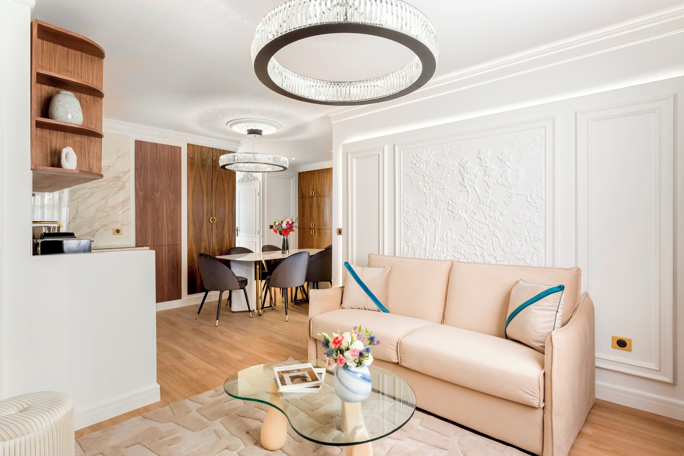 A modern living room with a sofa, a glass coffee table, and a dining area with chairs and a table.