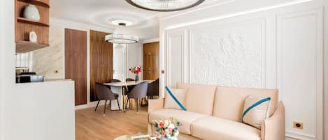 A modern living room with a sofa, a glass coffee table, and a dining area with chairs and a table.