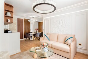 A modern living room with a sofa, a glass coffee table, and a dining area with chairs and a table.