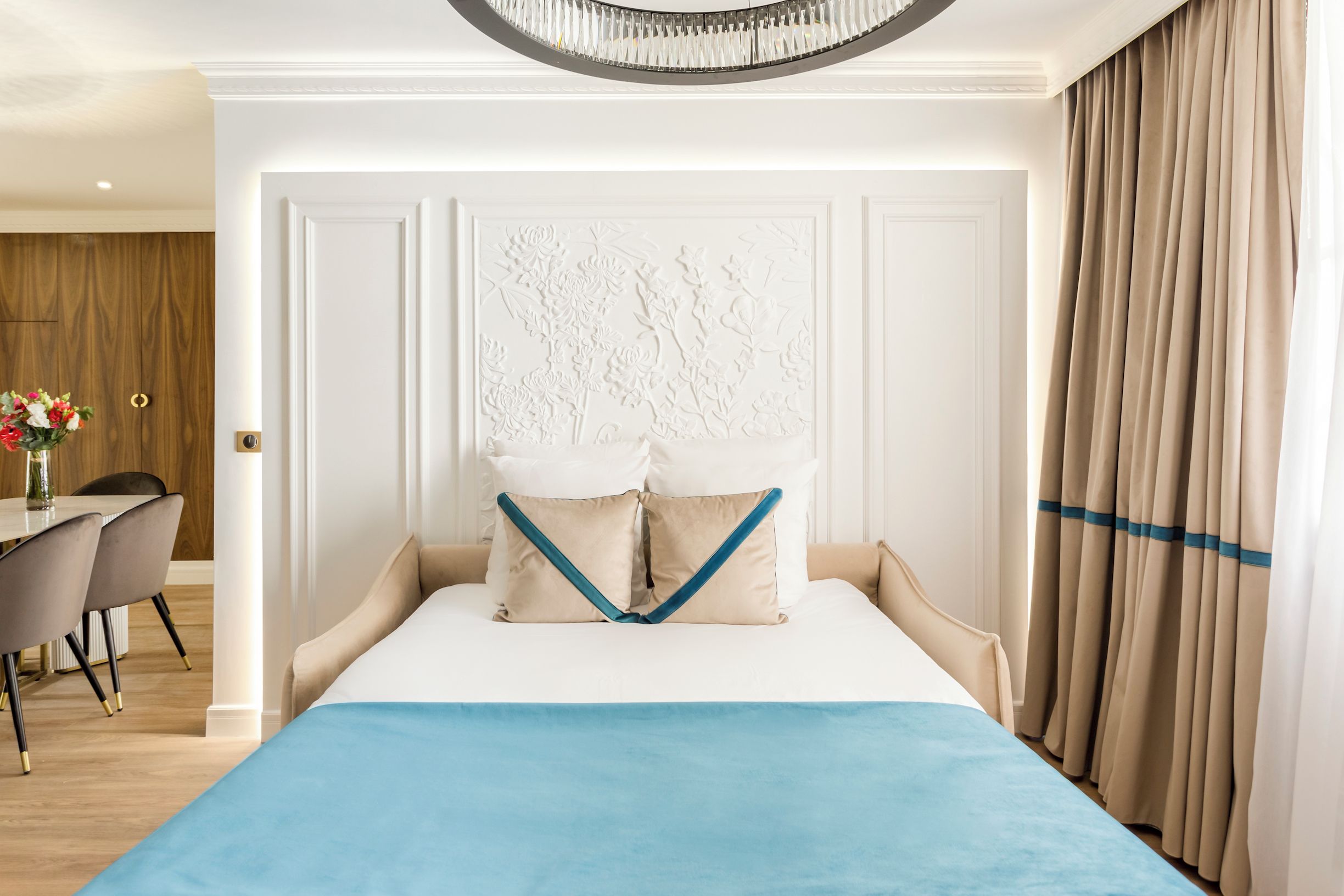 A hotel room with a bed, a dining area, and a view of the outdoors.