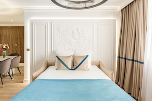 A hotel room with a bed, a dining area, and a view of the outdoors.