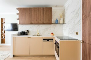 A modern kitchen with wooden cabinets, a marble backsplash, and a built-in dishwasher.