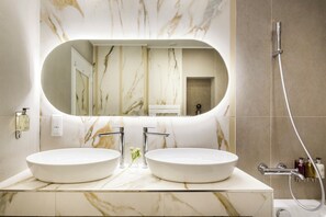 A bathroom with two sinks, a large mirror, and a shower.